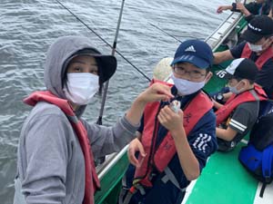 魚を釣り上げた男子児童と母親の写真
